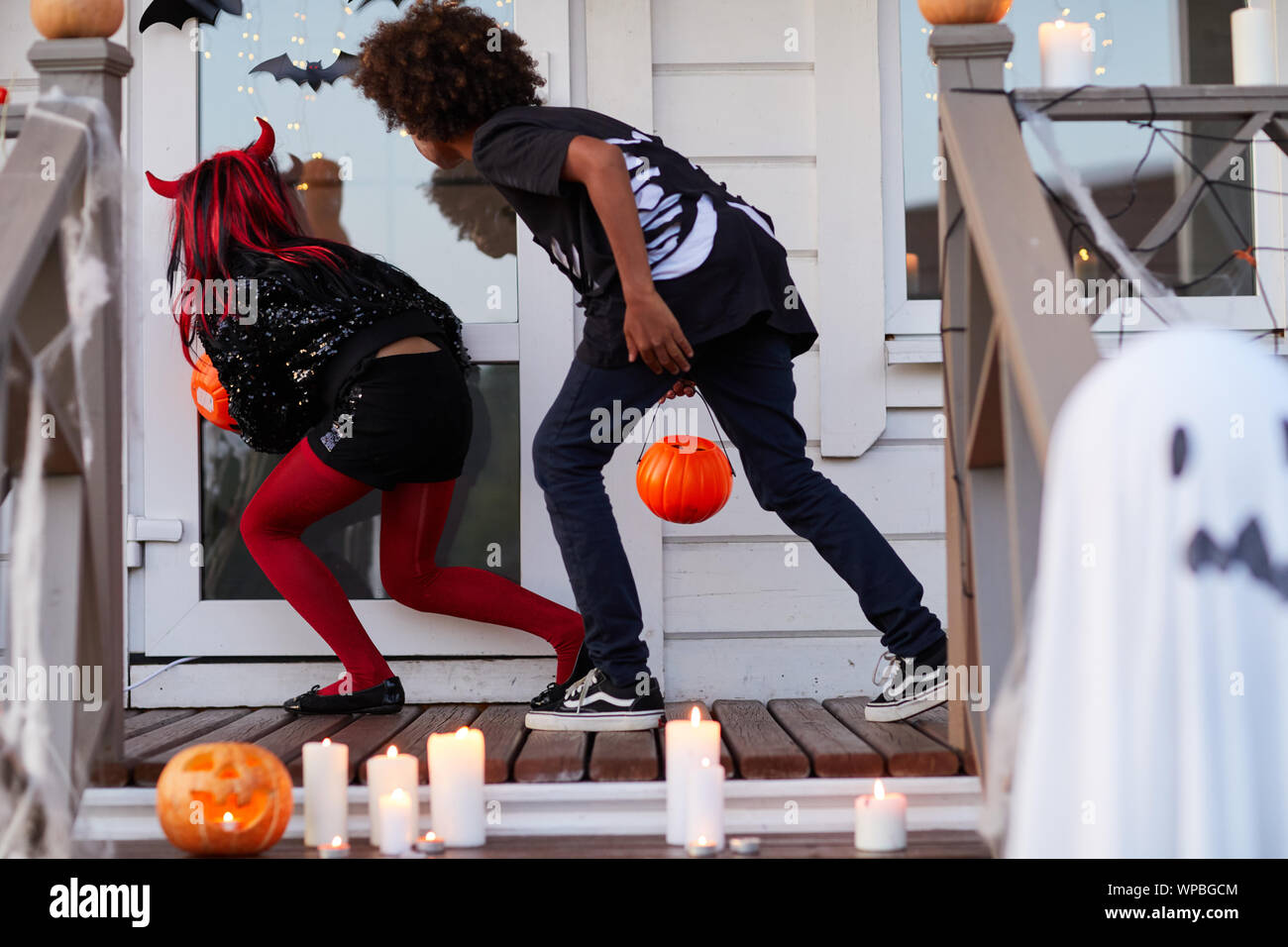 back-view-of-two-kids-sneaking-by-decorated-house-while-trick-or-treating-on-halloween-copy-sp...jpg