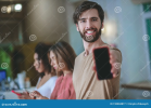 smiling-man-holding-smartphone-outstretched-arm-two-girls-behind-life-style-young-bearded-red-...png